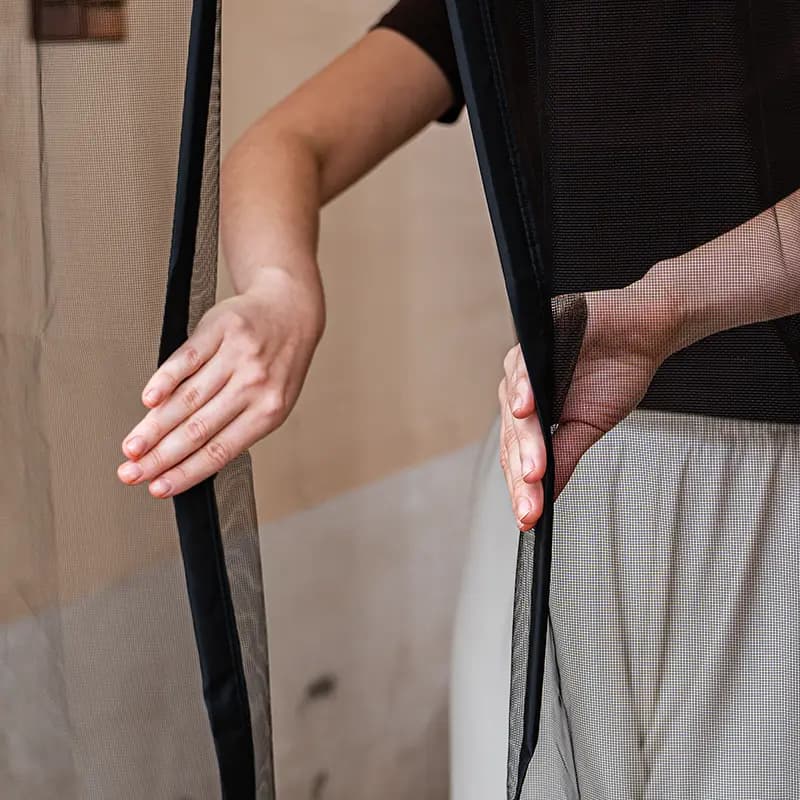 Hands holding and demonstrating a magnetic mesh screen door